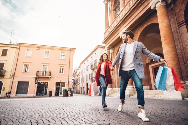 Jeune couple heureux avec sacs à provisions en cours d'exécution dans la ville — Photo