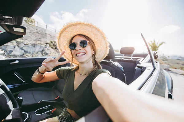 Felice giovane donna prende un selfie su una macchina convertibile in vacanza — Foto Stock