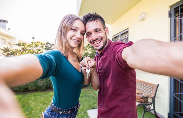 Selfie de una joven pareja de amantes sosteniendo la nueva llave de la casa — Foto de Stock