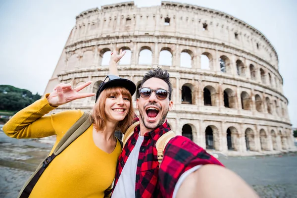 Happy couple of tourist smiling and taking a selfie at the Colosseum in Rome