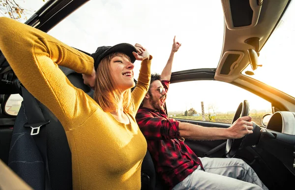 Šťastný pár v lásce řízení kabriolet auto při západu slunce na silnici — Stock fotografie