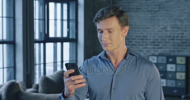 Zeitlupenporträt eines erfolgreichen selbstbewussten Geschäftsmannes, der Smartphone-Apps im Büro nutzt und lächelt. Geschäftsmannserien. 4k 4096x2160. — Stockvideo