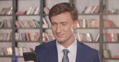 Tipik haber Smartphone içinde Office gülümseyen başarılı emin işadamı portresi hareket yavaş. İşadamı serisi. 4k 4096 x 2160.