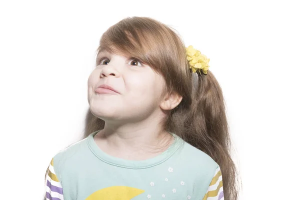 Маленькая эмоциональная девочка с изумлением смотрит вверх на белом фоне — стоковое фото