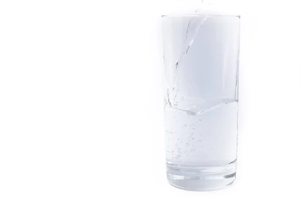 Água potável limpa derramada em um copo em um fundo leve — Fotografia de Stock