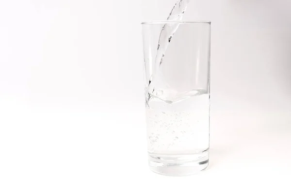 Clean drinking water poured into a glass on a light background — Stock Photo, Image