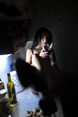 Bir bardak şarap mutfak masasında oturan çıplak kızla