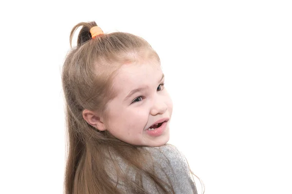 Una niña pequeña hace una cara y mira por encima de su hombro, aislado sobre fondo blanco — Foto de Stock
