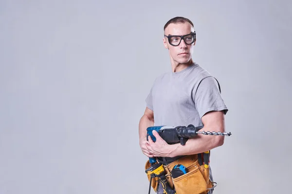 Mestre Construtor-finalizador em roupas de trabalho, com um perfurador em suas mãos — Fotografia de Stock