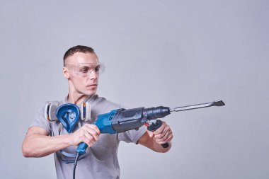 İş kıyafetleri içinde usta bir müteahhit, elinde bir detektörle.