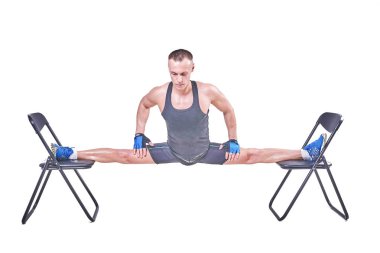 Yakışıklı bir erkek spor giyim beyaz bir arka plan üzerinde izole sandalyelere enine bir sicim, gerçekleştirir