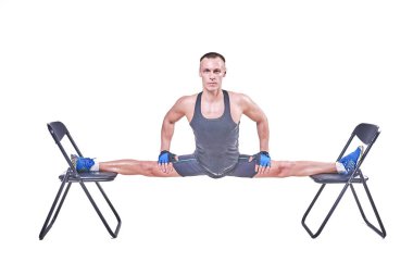 Yakışıklı bir erkek spor giyim beyaz bir arka plan üzerinde izole sandalyelere enine bir sicim, gerçekleştirir