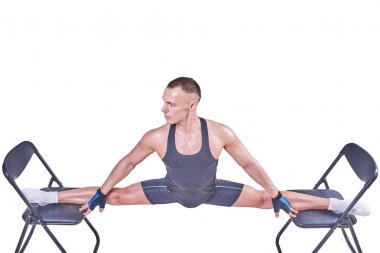 Yakışıklı bir erkek spor giyim beyaz bir arka plan üzerinde izole sandalyelere enine bir sicim, gerçekleştirir