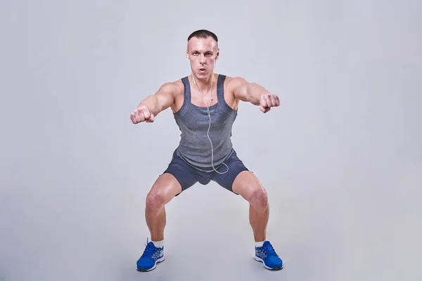 Bello uomo che esegue squat in abbigliamento sportivo — Foto Stock
