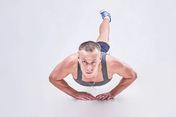 Un bell'uomo esegue push-UPS in abbigliamento sportivo — Foto Stock