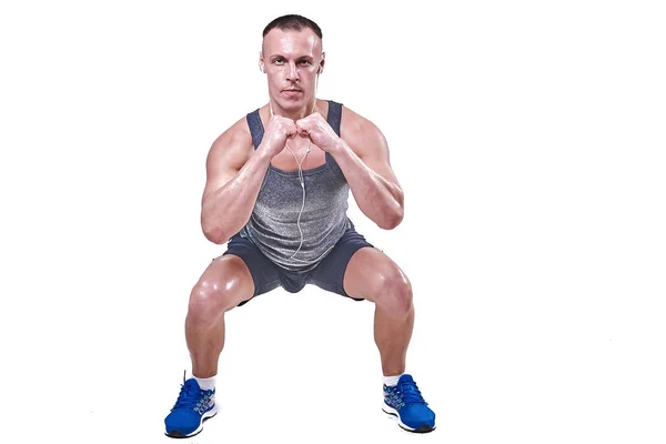 Knappe man uitvoeren van squats in sportkleding geïsoleerd op witte achtergrond — Stockfoto