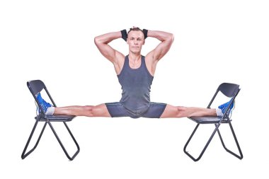 Yakışıklı bir erkek spor giyim beyaz bir arka plan üzerinde izole sandalyelere enine bir sicim, gerçekleştirir