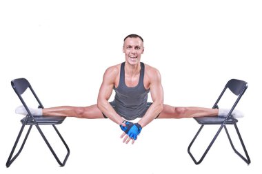 Yakışıklı bir erkek spor giyim beyaz bir arka plan üzerinde izole sandalyelere enine bir sicim, gerçekleştirir