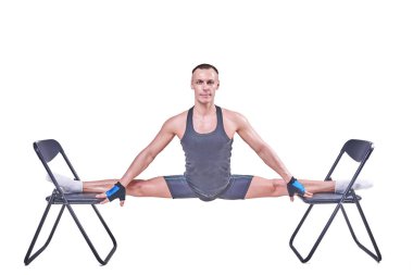 Yakışıklı bir erkek spor giyim beyaz bir arka plan üzerinde izole sandalyelere enine bir sicim, gerçekleştirir