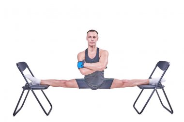 Yakışıklı bir erkek spor giyim beyaz bir arka plan üzerinde izole sandalyelere enine bir sicim, gerçekleştirir