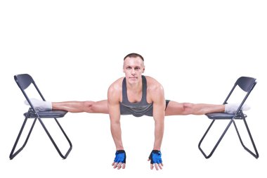 Yakışıklı bir erkek spor giyim beyaz bir arka plan üzerinde izole sandalyelere enine bir sicim, gerçekleştirir