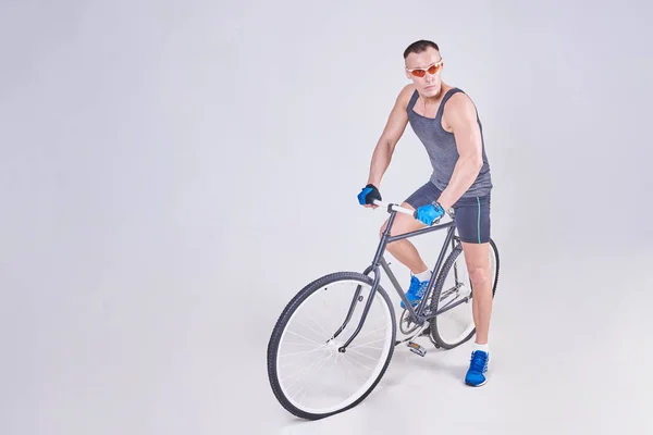Um homem de esportes bonito senta-se em uma bicicleta — Fotografia de Stock