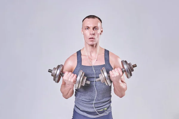 Красивый спортсмен делает упражнения с гантелями в руках — стоковое фото