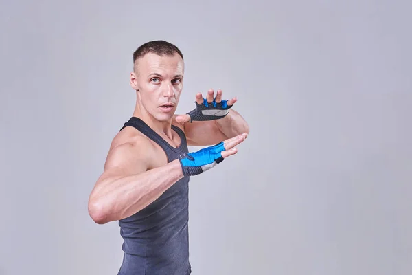 Un guapo deportista se para en una pose de lucha, con guantes —  Fotos de Stock