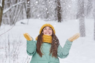 Güzel bir genç kız örgü şapkalı kar kış ormanda atar.