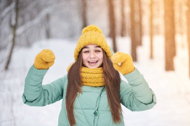 Güzel genç kız örme şapka içinde bir arka plan bir kış orman mittens Tamam gösterir