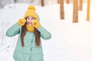 Güzel genç kız örme şapka içinde bir arka plan bir kış orman mittens Tamam gösterir