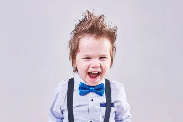 Malý chlapec výkřiky a úsměvy v modré luk, kravaty a šle — Stock fotografie