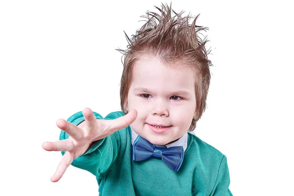Ένα όμορφο μικρό αγόρι, φορώντας ένα μπλε παπιγιόν και ένα πράσινο πουλόβερ, τεντώνει το χέρι του μπροστά του, να απομονωθεί σε λευκό φόντο — Φωτογραφία Αρχείου