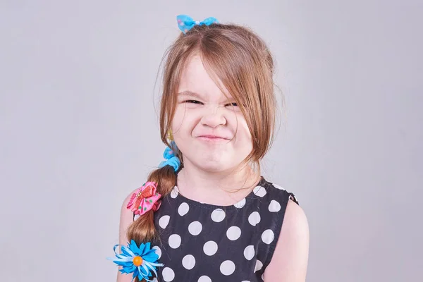 Uma linda menina contorcendo um rosto engraçado — Fotografia de Stock