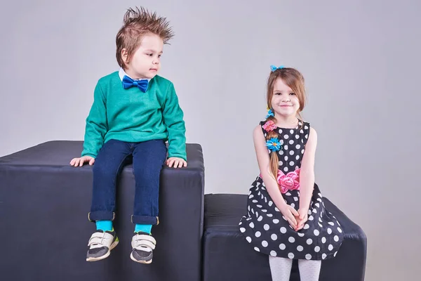 Gyönyörű kisfiú és a lány ül a fekete kockák — Stock Fotó