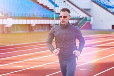 Koşu bandı stadyum üzerinde çalışan yakışıklı atletik erkek