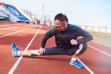 Adam atlet Stadı nda yolda germe yapıyor.