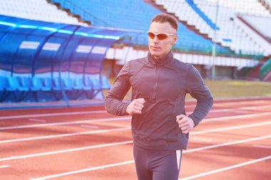 Koşu bandı stadyum üzerinde çalışan yakışıklı atletik erkek