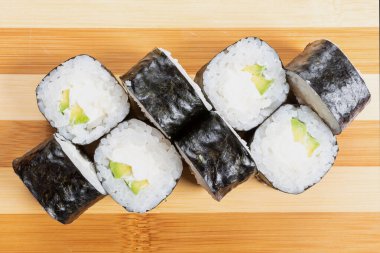 Suşi, peynirli makarna ve avokado. Tahtada..