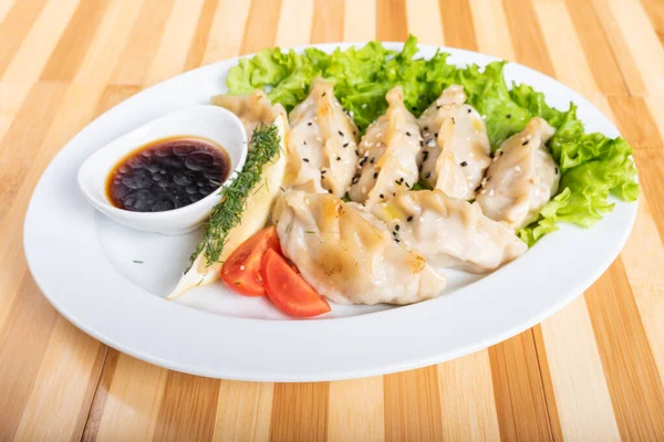 Gyoza en un plato, con hierbas y salsa . — Foto de Stock