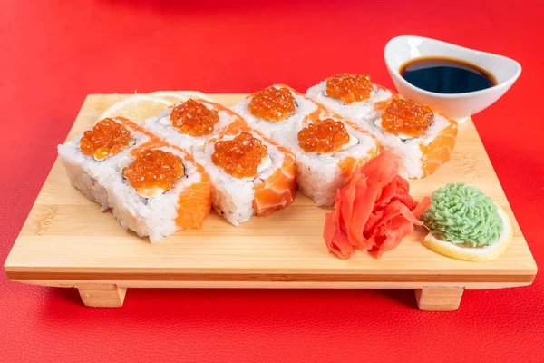 Sushi, con requesón, salmón y caviar. En el tablón. Sobre un fondo rojo . — Foto de Stock