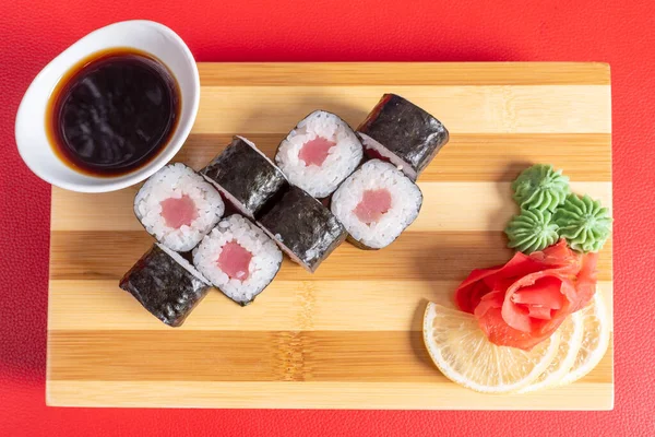 Sushi, rollos de atún, en la tabla. Sobre un fondo rojo . — Foto de Stock