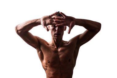 Atletik, bronzlaşmış bir adam, ellerini önünde tutuyor. Çıplak bir gövdeyle. Beyaz bir arkaplanda izole edilmiş.