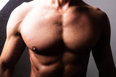 Güzel, atletik, erkek gövdesi. Kontrastlı ışıkta. Parlak ve suyla.