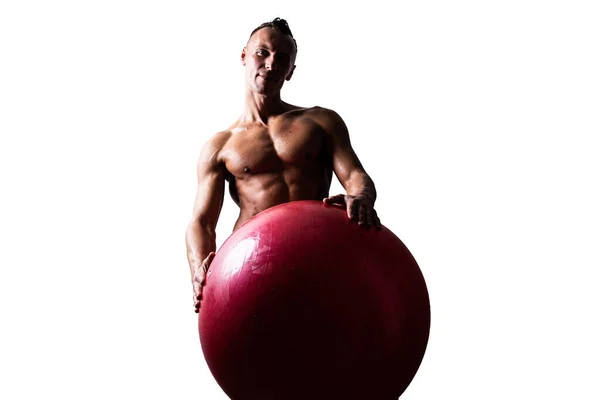 Atletische, gebruinde man, verstopt achter een rode, gymnastische bal. Geïsoleerd op een witte achtergrond. — Stockfoto