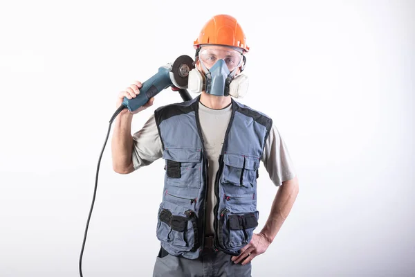 Um construtor em um capacete e um respirador, com um moedor de ângulo em seu ombro . — Fotografia de Stock