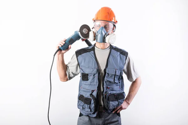 Un constructor en un casco y un respirador, con una amoladora angular en el hombro . — Foto de Stock