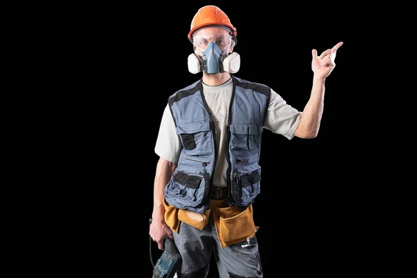 Construtor com um perfurador, em um capacete e um respirador. Pontos à direita . — Fotografia de Stock