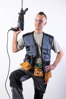 İnşaatçı matkabı yukarıda tutuyor. İnşaatta boşaltma ve güvenlik gözlüğü..