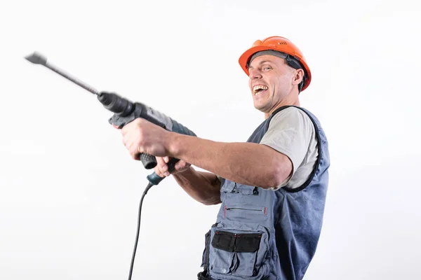 Un constructor con una expresión divertida, en un casco, con un perforador . —  Fotos de Stock